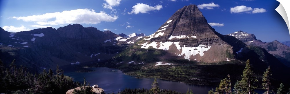 An immense mountain in front of a large lake is photographed in wide angle view.