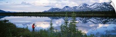 Mountain scene with lake reflection, fisherman at water's edge, spring, Alaska Range, Alaska