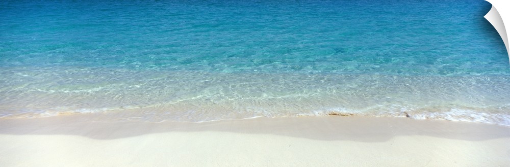 Panoramic photograph of shoreline with wet sand and crystal clear water.