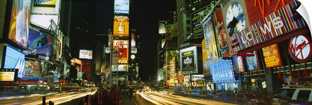 Wide angle photograph of Times Square in New York City, brightly lit at night.