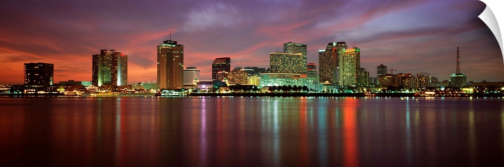 Panoramic photograph of the Crescent City skyline at twilight reflecting in the water.