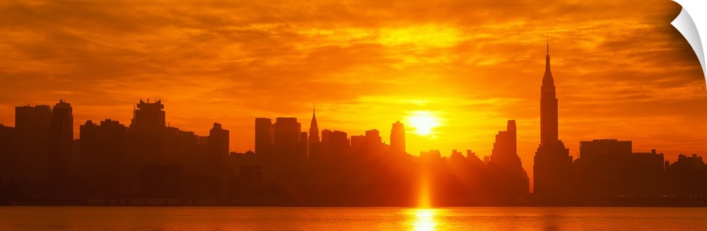 This panoramic photograph shows the sun rising over Manhattan and making silhouettes of the city skyline.