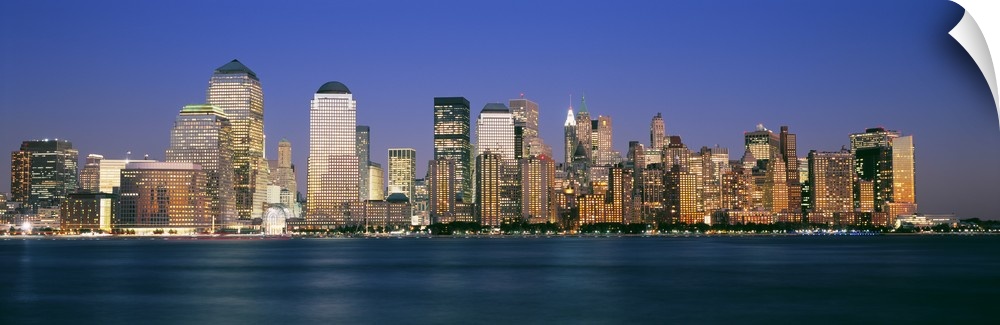 Panoramic photograph taken of smaller skyscrapers that sit on the edge of water in New York City.