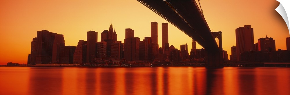 Under the Brooklyn Bridge looking at lower Manhattan with the twin towers and the financial district glowing in the sunset.