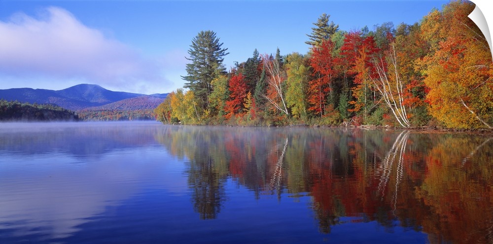 Big, horizontal photograph of autumn trees reflecting along the shoreline of the Franklin Falls Pond in New York, mountain...