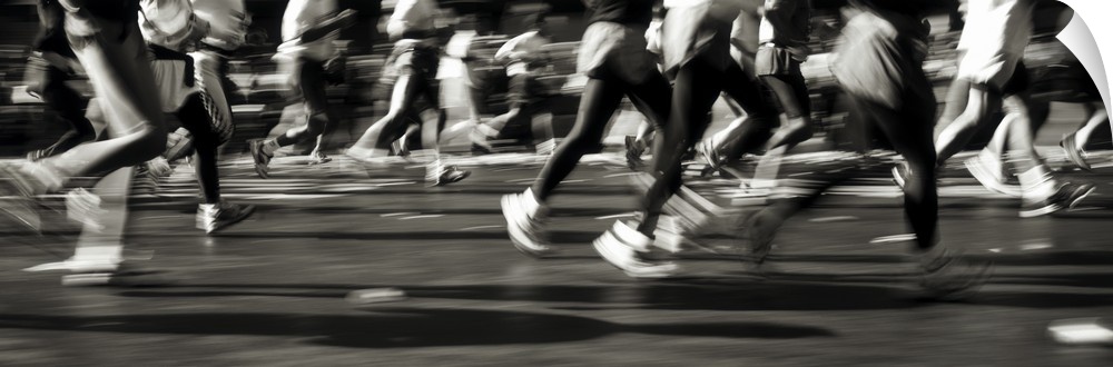 Large, horizontal photograph of many runners from their waists down, running in a blur in the New York Marathon.
