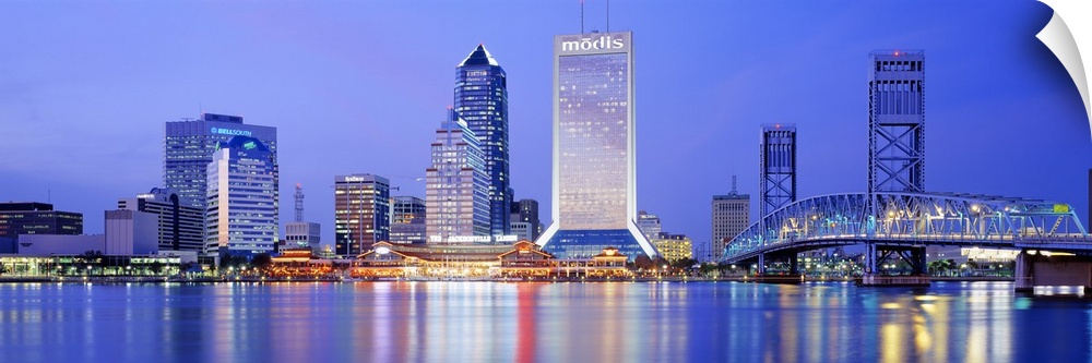 This large panoramic photograph is of the Jacksonville skyline with it's buildings lit up at night and reflecting in the w...