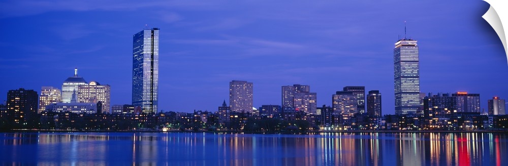 Panoramic night skyline with building lights reflecting onto the waterfront.
