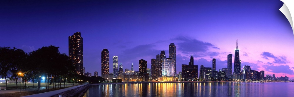 A panoramic of the Chicago cityscape lit up at dusk and reflecting on Lake Michigan.