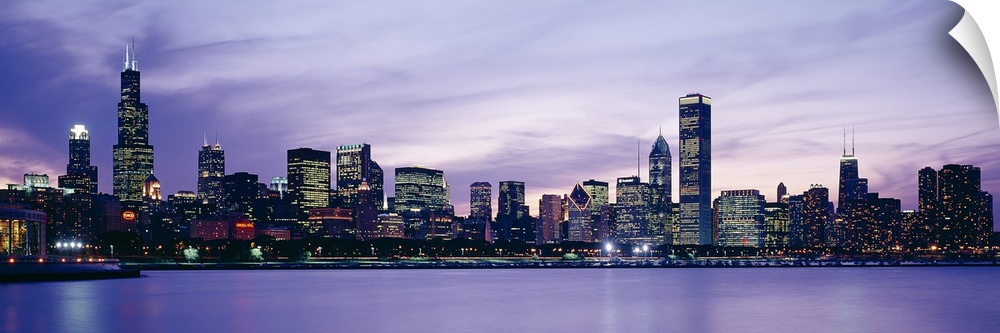 Big canvas photo of an illuminated cityscape along a smooth waterfront at dusk.
