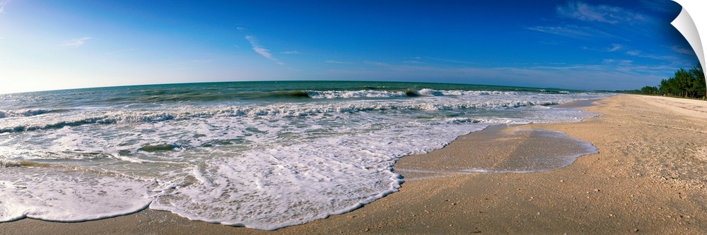 Panoramic photograph displays waves from the Gulf of Mexico as they gently break onto a sandy beach within Florida.
