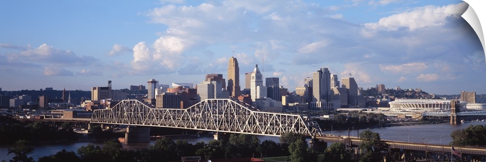 Wide angle photograph taken of the Cincinnati skyline from a distance with a clear view of the bridge into the city.