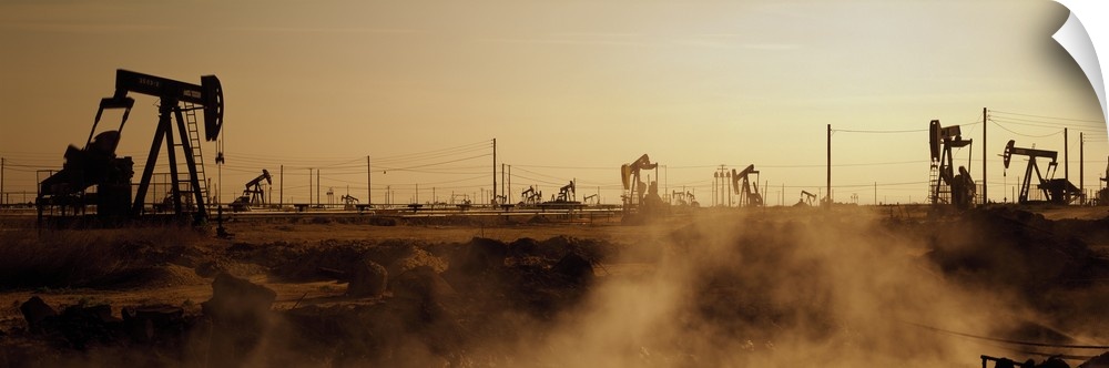 Panoramic photograph of many oil drills in a vast filed at sunset in Maricopa, Kern County, California.