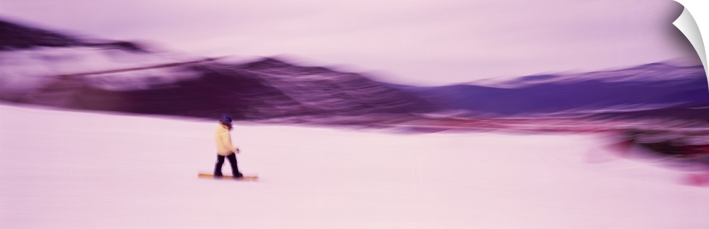 Panoramic photo of someone snowboarding down a mountain printed on canvas.