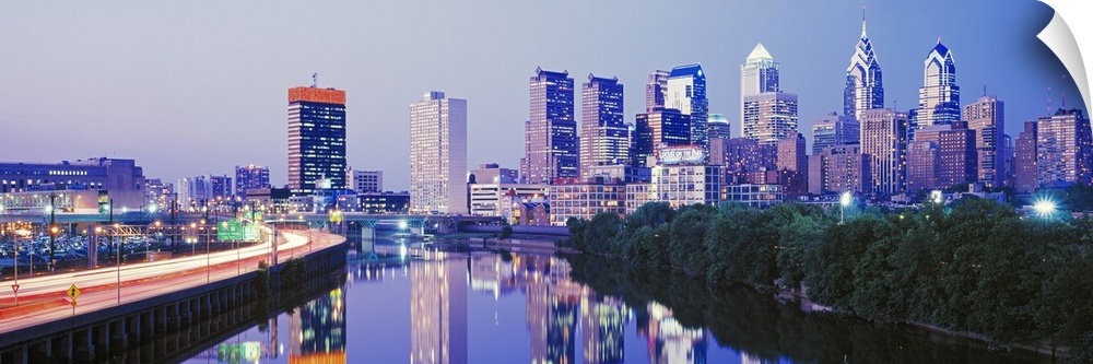 This artwork is a panoramic canvas of the city skyline reflecting in the river water at dusk.