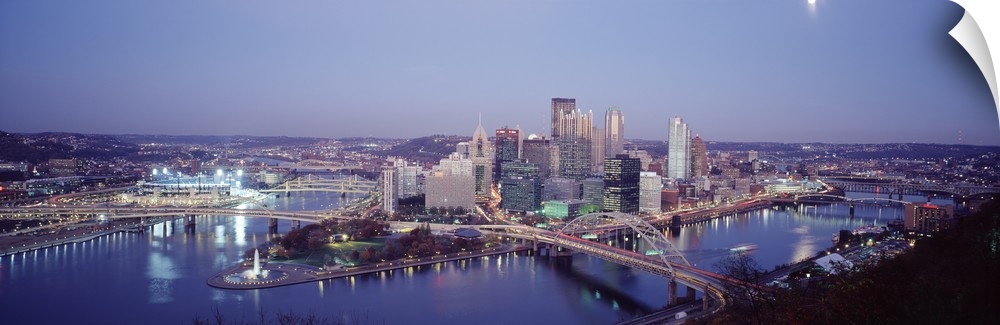 Panoramic photograph of city skyline at dusk.  Iconic buildings, bridges, and waterways are featured.