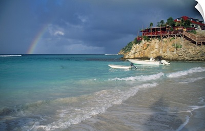 Rainbow over Caribbean Sea, boats docked cliffside.