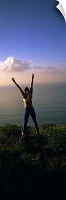 Rear view of a young woman exercising on a hill