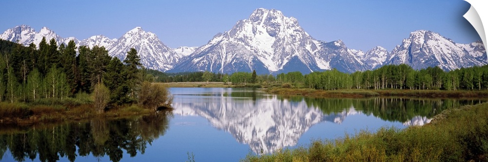 Panoramic photograph on a giant canvas of mountain reflections in the Snake River, surrounded by forest in the Grand Teton...