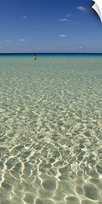 Rippled water surface of the sea with a tourist in the background, Spiaggia Dei Conigli, Italy