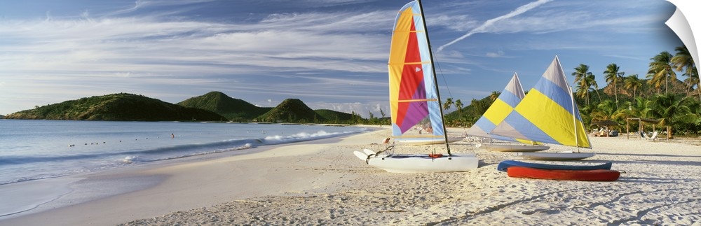 Panoramic photograph of colorful boats on beach with ocean and mountains in the distance.