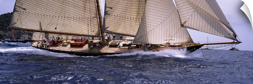 The body of a large sail boat is photographed in wide angle view as one side leans down into the water.