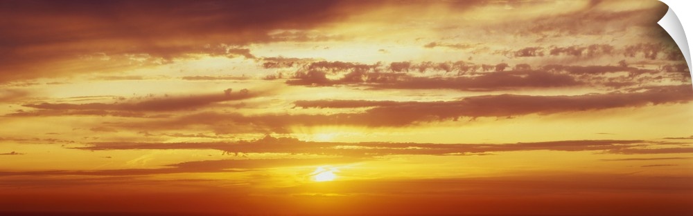 Panoramic photo on canvas of a brightly colored sunset with horizontal clouds.