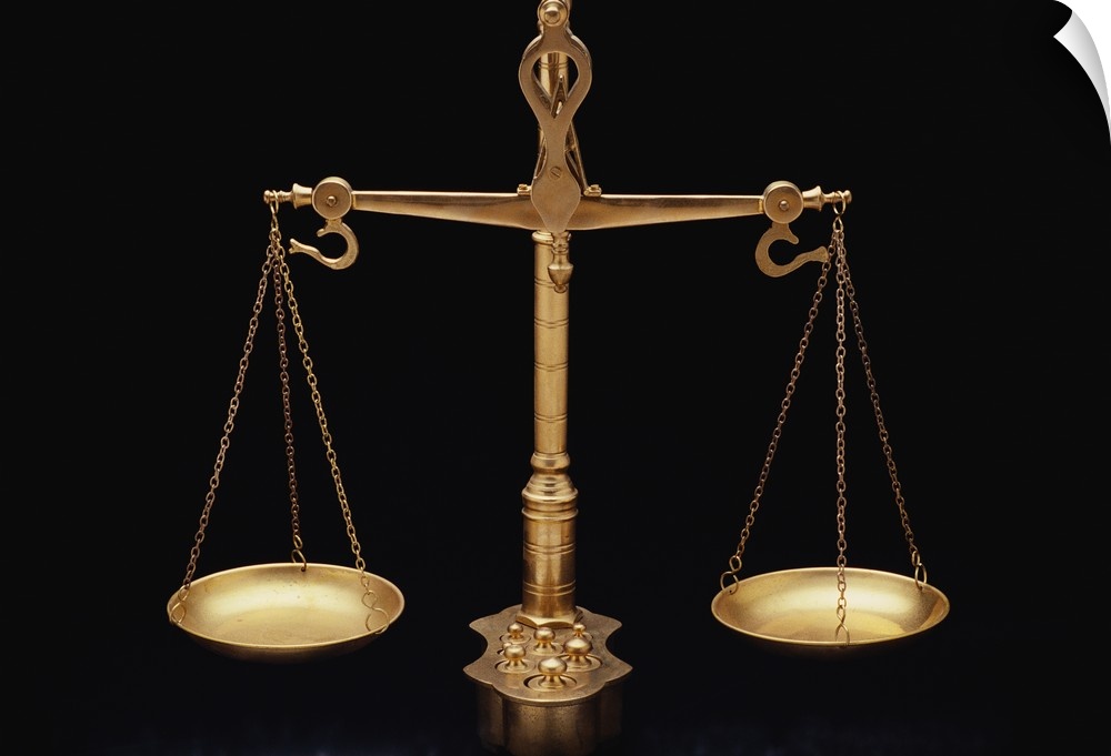 Photograph taken of gold scales of justice against a black background.