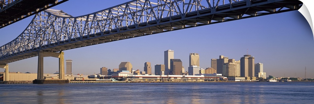 Part of the New Orleans skyline is photographed from a distance below the Crescent City Connection bridge.