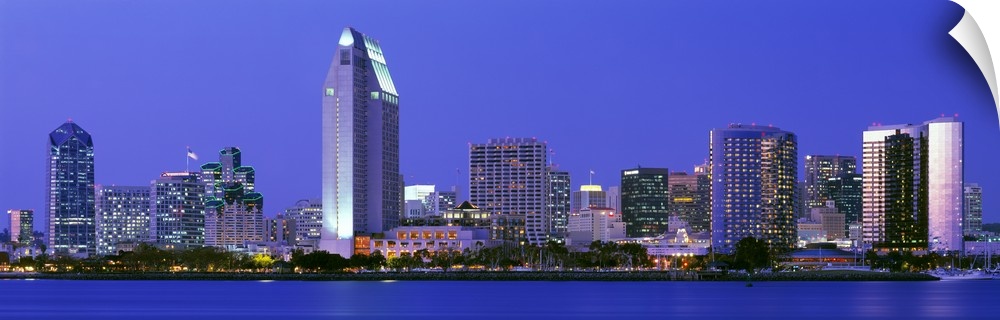 Skyscrapers in San Diego are illuminated and photographed in panoramic view from across a body of water.