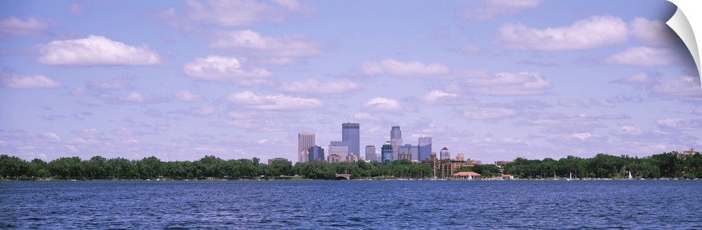Panorama depicting Minneapolis downtown with a cloud-filled sky and a view of Chain of Lakes Park in Minnesota.