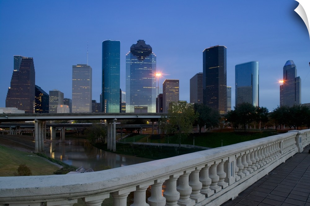 Street view photograph of tall buildings lit up in a city at dusk.