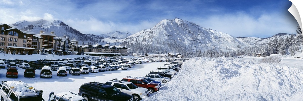 Snow covers the mountains, ground and cars that sit parked at a large ski resort in Lake Tahoe.