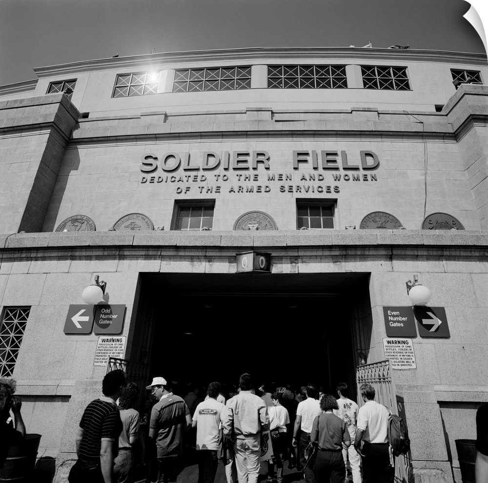 A black and white photograph of fans entering the Chicago Bears stadium with the fields name displayed just above them.