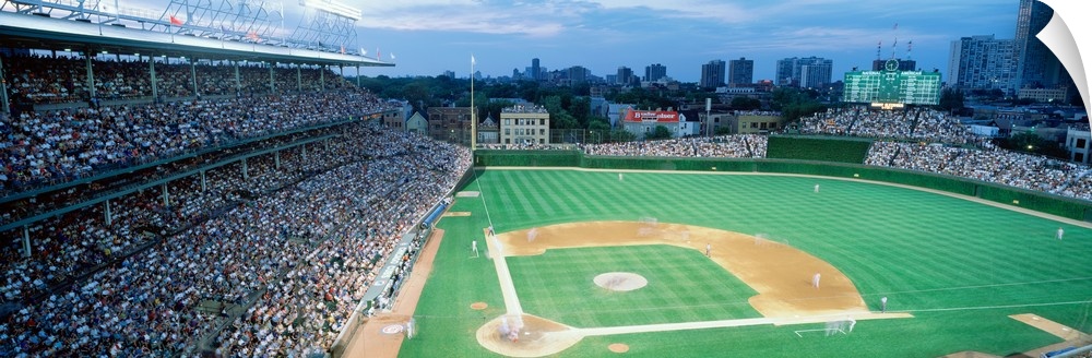 Panoramic shot of Wrigley Field and the baseball diamond during a game as the crowd cheers.
