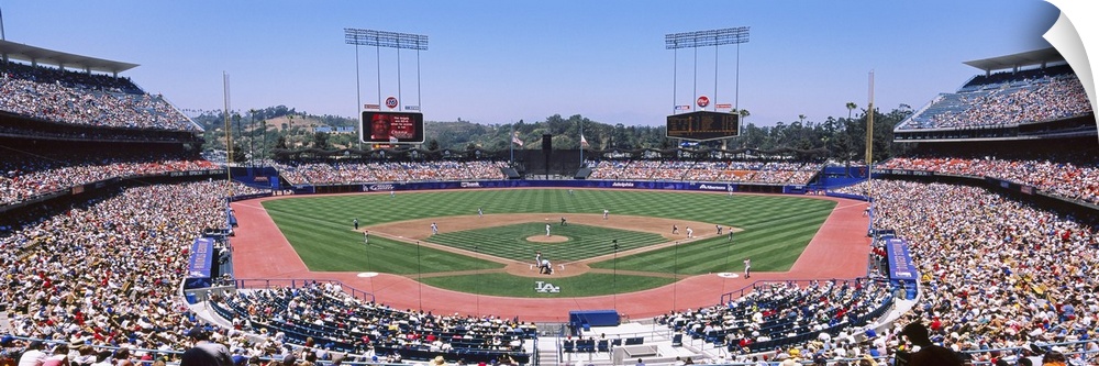 Panoramic photograph of inside baseball stadium with game in full swing.  The stands are packed with fans.