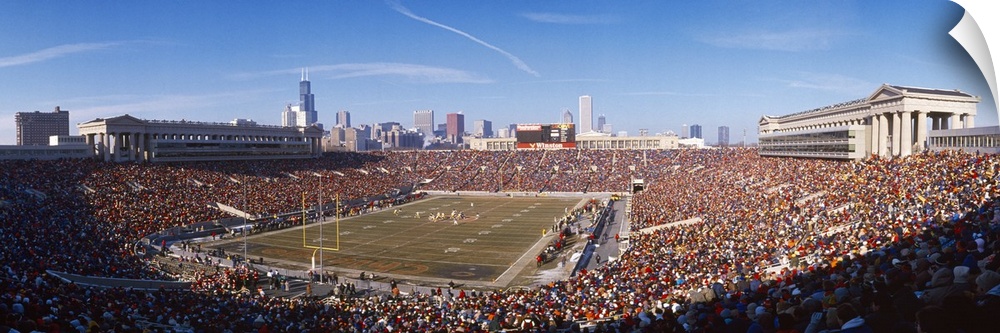 A crowded stadium full of sports fans ready to watch the Chicago Bears game under a clear blue sky, with the city skyline ...