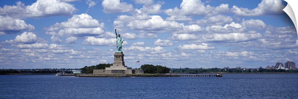 A panorama of the Statue of Liberty and the NY Harbor with a blue sky in background.