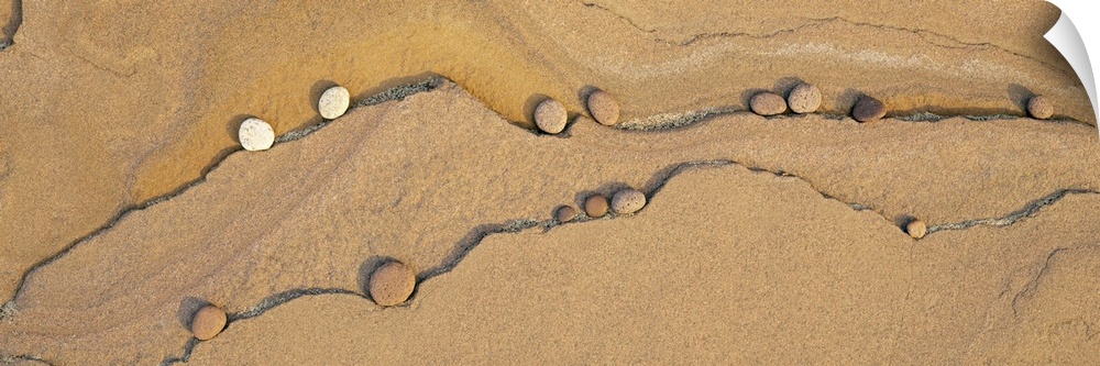 Soft pebbles lay in the cracks of sand near Lake Superior and are pictured in panoramic view.