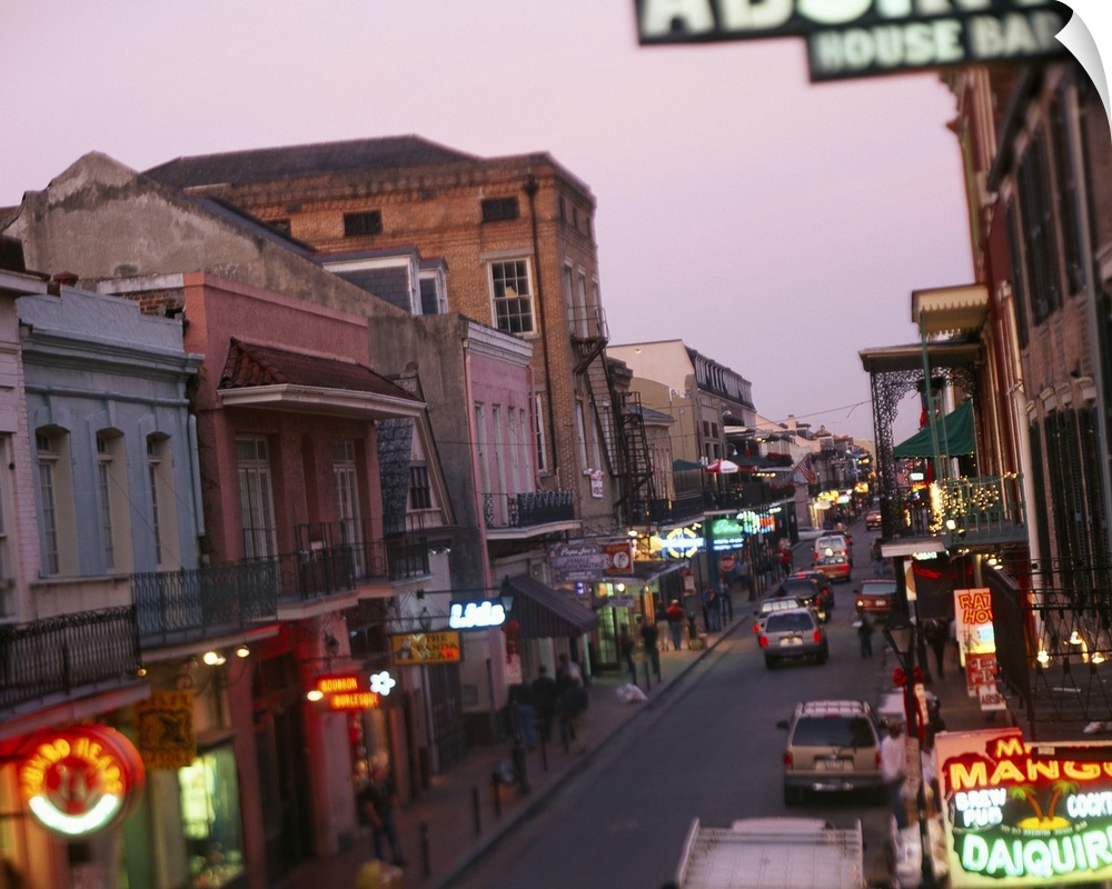 Landscape, large photograph looking down Bourbon Street in New Orleans, Louisiana.  Rows of storefronts with neon signs li...