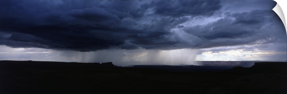 A wide angle shot taken of an immense storm over canyons in Utah.