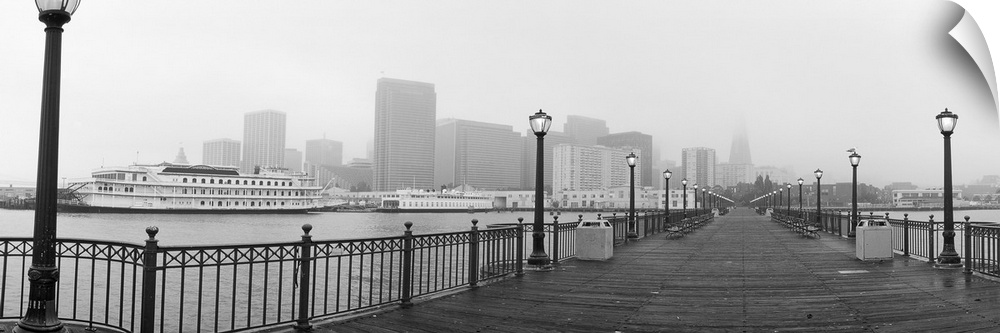Black-and-white panoramic photo of an empty San Francisco pier on a foggy day in California.