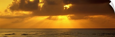 Sunbeams radiating through clouds over the ocean