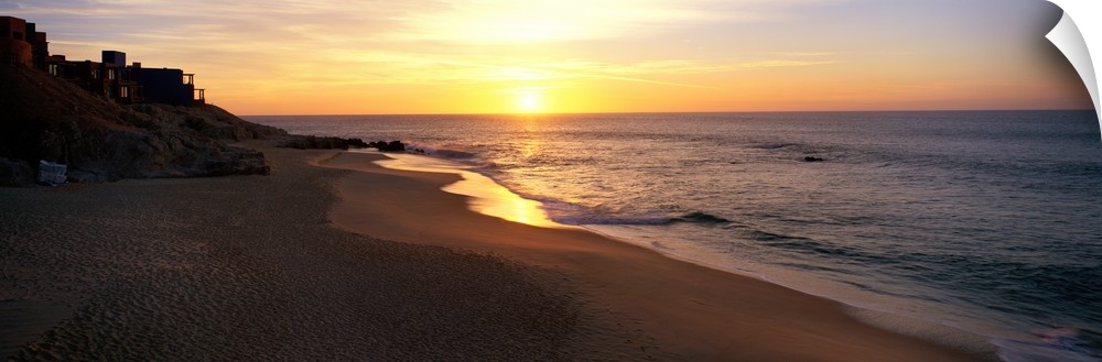 Panoramic photo of the sun rising over the beach in Los Cabos, Mexico.