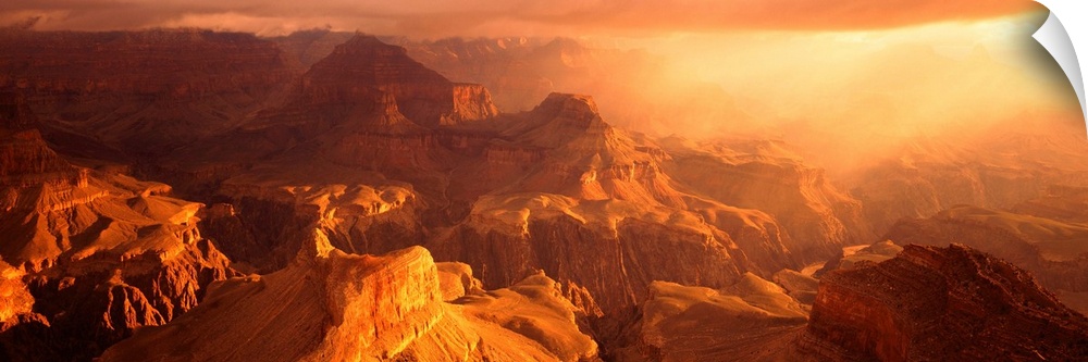 A panoramic photograph of the sunos rays shining on the rocky plateaus emerging from the canyon.