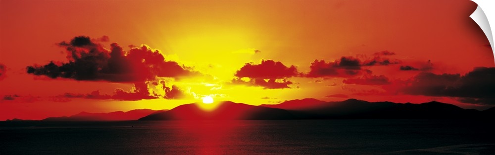 Panoramic photograph of a fiery sunset over a mountain landscape on the horizon, in the British Virgin Islands.