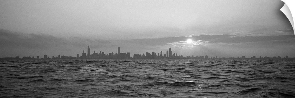 Wide angle photograph of sunset over choppy waters of Lake Michigan, the Chicago skyline in the distant horizon.