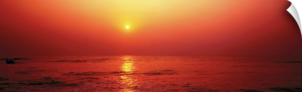Panoramic photograph taken of the sun as it begins to set in the sky. The entire picture has a warm tone to it.