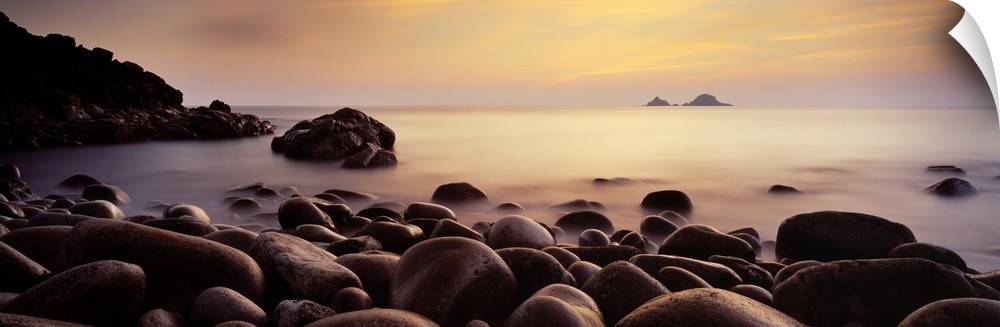 Large stones create a rocky coast line in England was the sun sets over the misty Atlantic Ocean.