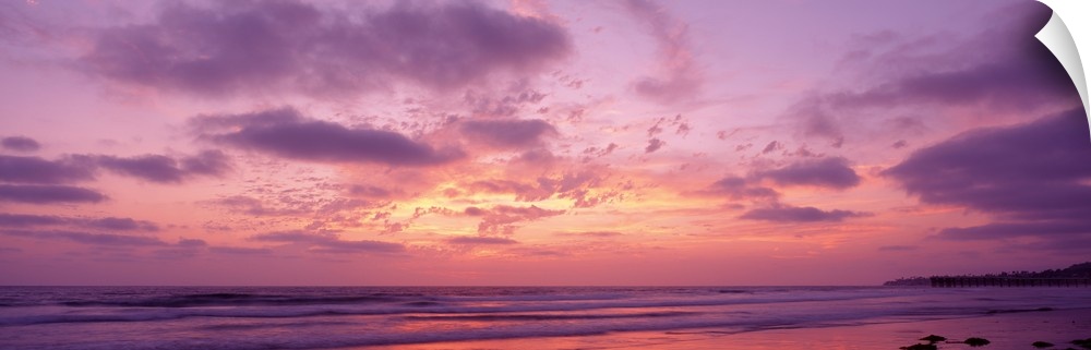 Panoramic photograph of a pastel sunset over the Pacific Beach in San Diego, California, with swirling clouds in the sky.